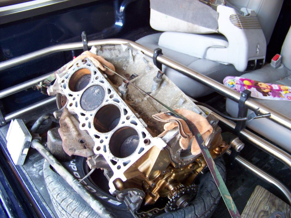 Engine block with pistons visible, resting in the bed of a truck