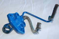 1979 Ford F-150 - A close-up view of a blue metal automotive part, possibly a linkage or bracket, against a plain background.