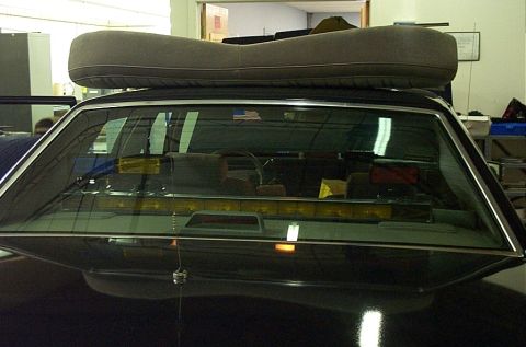 1991 Ford LTD Crown Victoria - View into the interior of a sedan, showing a light bar across the rear window and a large cushion secured to the roof.