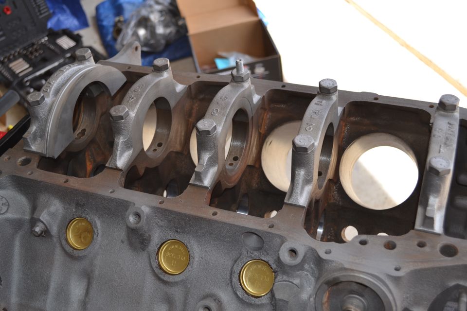 Engine block with crankshaft bearing caps installed. Some brass plugs are visible on the side