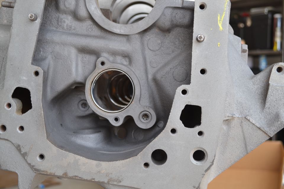 Gray metal engine block with circular openings and bolt holes. A silver ring is visible inside one opening
