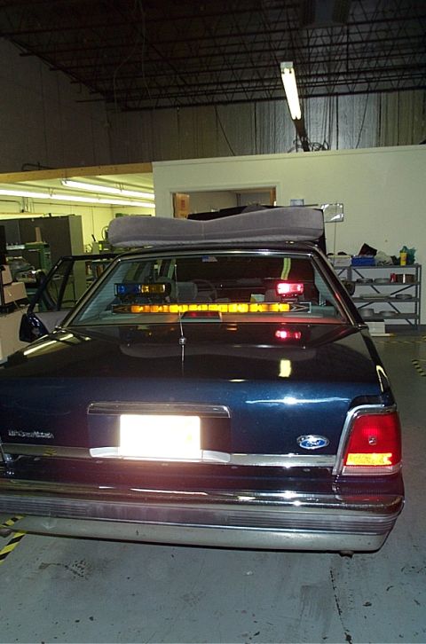 1991 Ford LTD Crown Victoria - Rear view of a dark blue sedan with an emergency light bar installed on the roof and inside the interior.