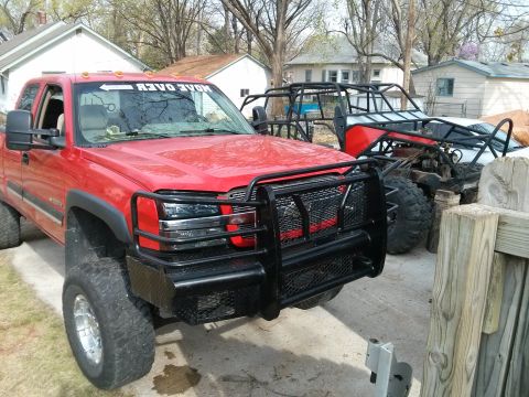 1986 Ford Bronco - Two off-road vehicles, a red pickup truck and a buggy, are parked outdoors.