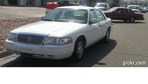 2000 Mercury Grand Marquis - A white 2000 Mercury Grand Marquis is parked in a lot with another vehicle behind it.