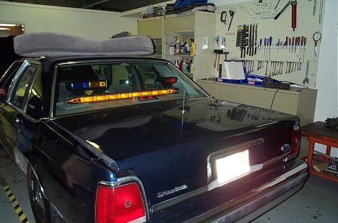 1991 Ford LTD Crown Victoria - Rear view of a 1991 Ford Crown Victoria LTD, equipped with emergency lights and a large cushion on its roof.