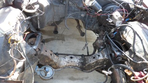 1972 Ford Ranchero - The front frame and suspension components of a vehicle, showing exposed wiring and rusted metal.