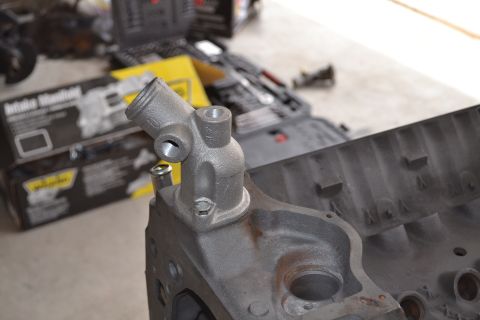 1981 Ford F-250 - Close-up of an engine block and thermostat housing, with tools and parts in the background.