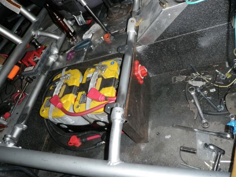 1961 International Scout 800 - The interior of a vehicle shows a dual battery setup with a roll cage, tools, and a bottle.