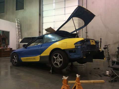 1995 Ford Probe - This two-tone vehicle is in a garage, with its hood and rear section open, and is elevated on jack stands.