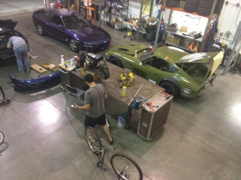 1995 Ford Probe - A purple coupe sits in a workshop alongside other vehicles and parts.