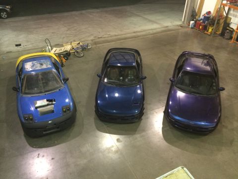 1995 Ford Probe - Three coupes are parked in a garage, with one showing its engine bay.