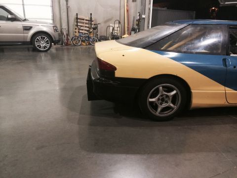 1995 Ford Probe - A yellow and blue car is parked in a garage next to a silver SUV.