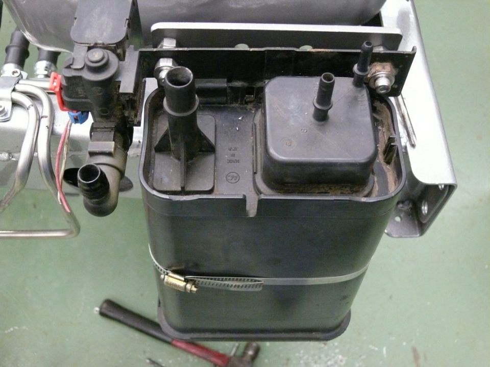 Black plastic evaporative emissions canister with metal hose clamp and various hoses attached