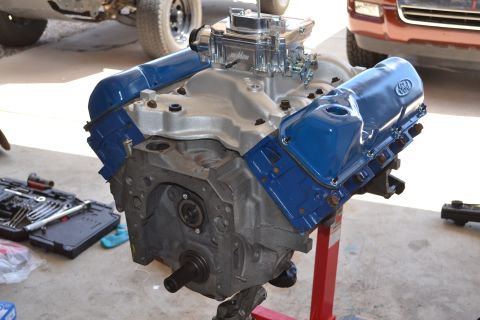 1981 Ford F-250 - Engine assembly with blue valve covers and chrome carburetor, tools and another vehicle visible in the background.