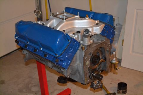 1981 Ford F-250 - A blue Ford engine, likely a V8, is displayed on a red engine stand, revealing its internal timing components and fuel pump.