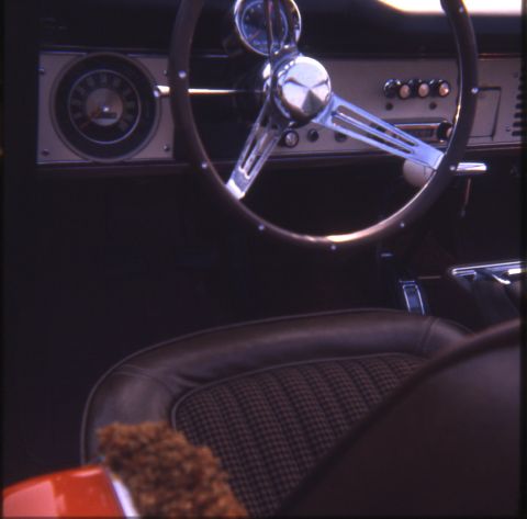1996 Ford Bronco - The interior of a classic SUV features a vintage steering wheel and dashboard, with a distinctive houndstooth seat pattern visible.