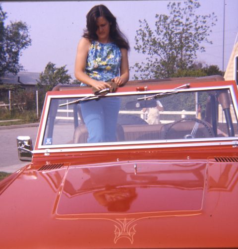 1996 Ford Bronco - A woman leans on the windshield frame of a red convertible SUV with custom pinstriping.