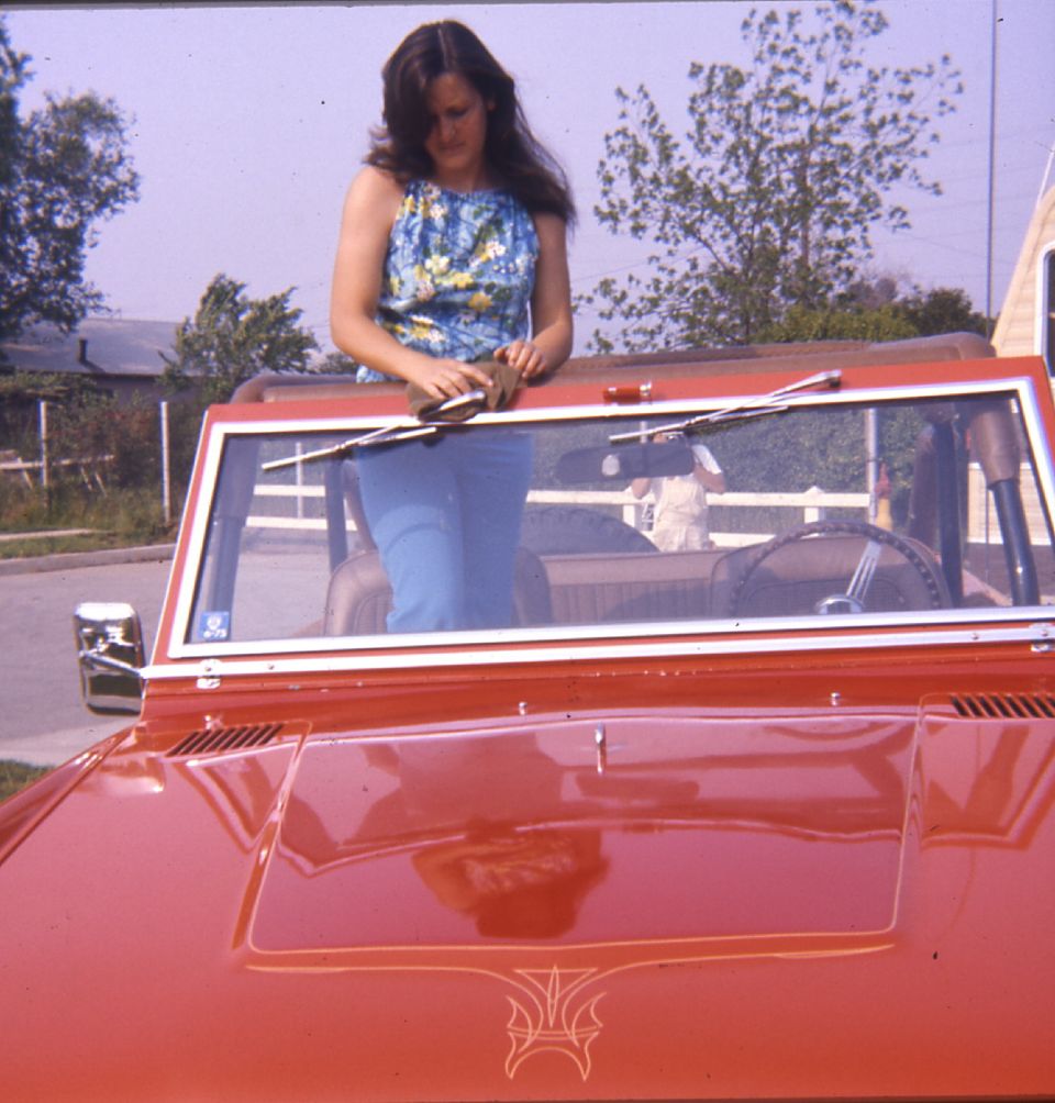 Red convertible SUV with pinstriping on the hood, woman in floral top and blue jeans