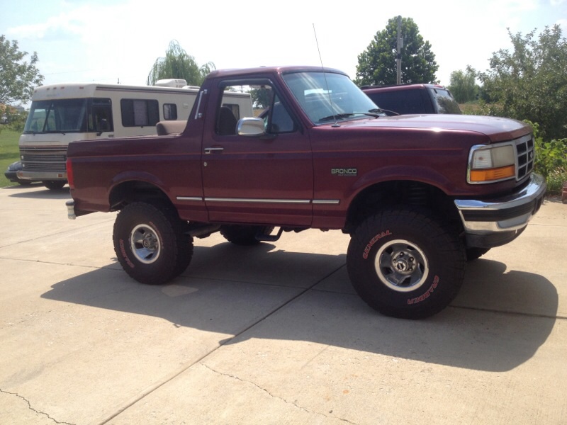 Maroon 1996 Ford Bronco with lifted suspension and off-road tires parked on a concrete driveway