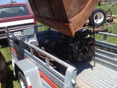 1996 Ford Bronco - An engine is being unloaded into a trailer, with a maroon truck visible behind it.
