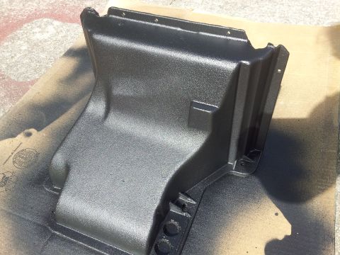 1976 Ford Ranchero - A black plastic air conditioning duct is shown after being spray-painted, resting on a piece of cardboard.