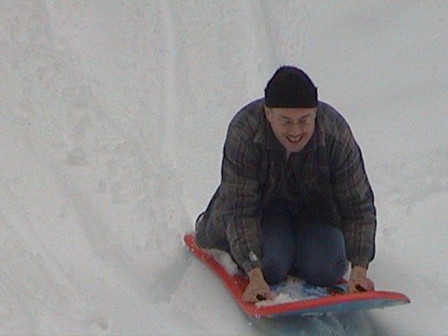 Man on a red sled going down a snowy hill