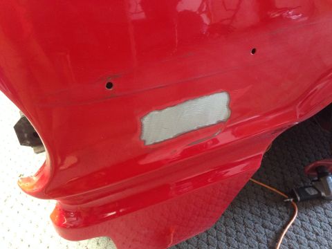 1964 Ford Fairlane - A close-up view of a red car's body panel undergoing repair, showing filler and drill holes.