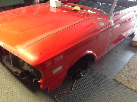 1964 Ford Fairlane - A red 1964 Ford Fairlane convertible is shown during its restoration process, with the front quarter of the vehicle visible.