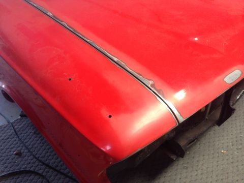 1964 Ford Fairlane - Red car hood seam shows signs of repair work and minor damage.