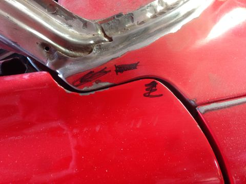 1964 Ford Fairlane - Detail shot of a red car's body panel showing some repair marks and a handwritten symbol.