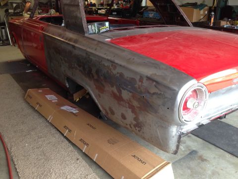 1964 Ford Fairlane - A 1964 Ford Fairlane convertible is shown in a workshop, with its rear quarter panel in need of repair and restoration.