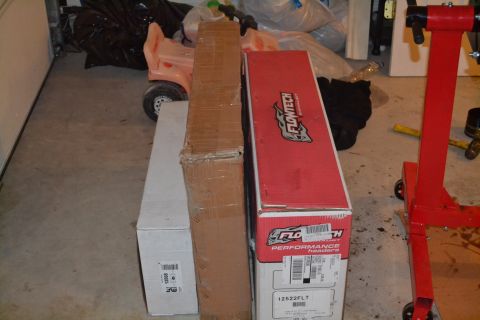 1981 Ford F-250 - Boxes of car parts, including Flowtech headers, are stored in a garage next to a child's ride-on toy.