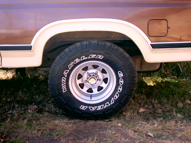 Side view of a brown Ford Bronco's rear wheel and fender with Goodyear Wrangler tires
