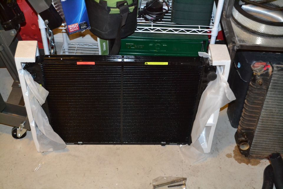 New black radiator in packaging, next to an old radiator