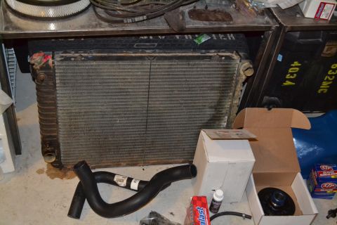1981 Ford F-250 - A radiator and hoses are shown on a concrete floor with various boxes and automotive parts.