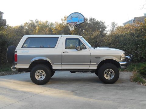 1994 Ford Bronco - This two-tone white and silver Ford Bronco is shown from the side, a spare tire on the rear.