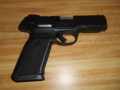 1994 Ford Bronco - A black semi-automatic pistol rests on a wooden surface. The Ruger logo is visible on the grip.