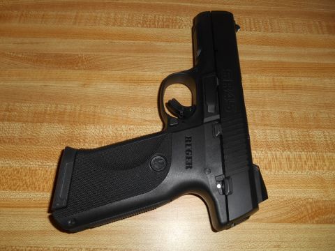 1994 Ford Bronco - A black Ruger SR45 pistol is shown resting on a wood-grain surface.