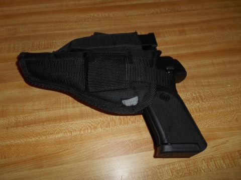 1994 Ford Bronco - A black pistol is secured in a black fabric holster, resting on a wood-grain surface.