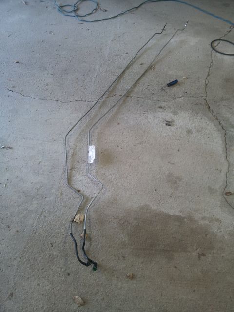 2002 Chrysler 300M - Two metal fuel lines are shown on a concrete floor, possibly for a vehicle repair.