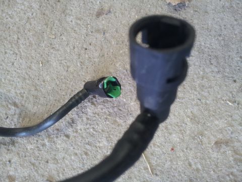2002 Chrysler 300M - Close-up of two disconnected fuel line connectors, one with a green insert, lying on a concrete surface.