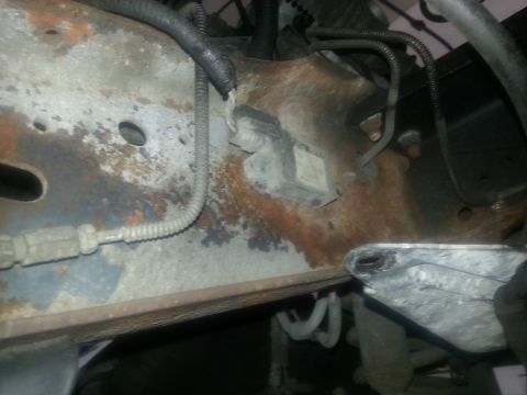 1994 Ford Bronco - This image shows heavily rusted frame components and various wires and hoses attached to the vehicle's undercarriage.