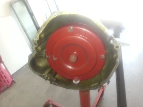1994 Ford Bronco - A transmission torque converter, a red bell housing, is shown mounted on a stand, likely for repair or inspection.