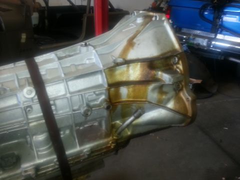 1994 Ford Bronco - Transmission pan with significant oil leakage and signs of impact.