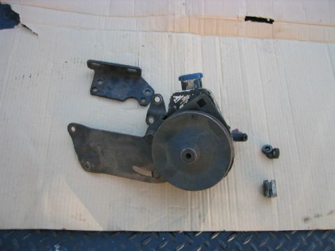 1973 Ford F-100 - A disassembled power steering pump assembly, including brackets and nuts, is laid out on a surface.