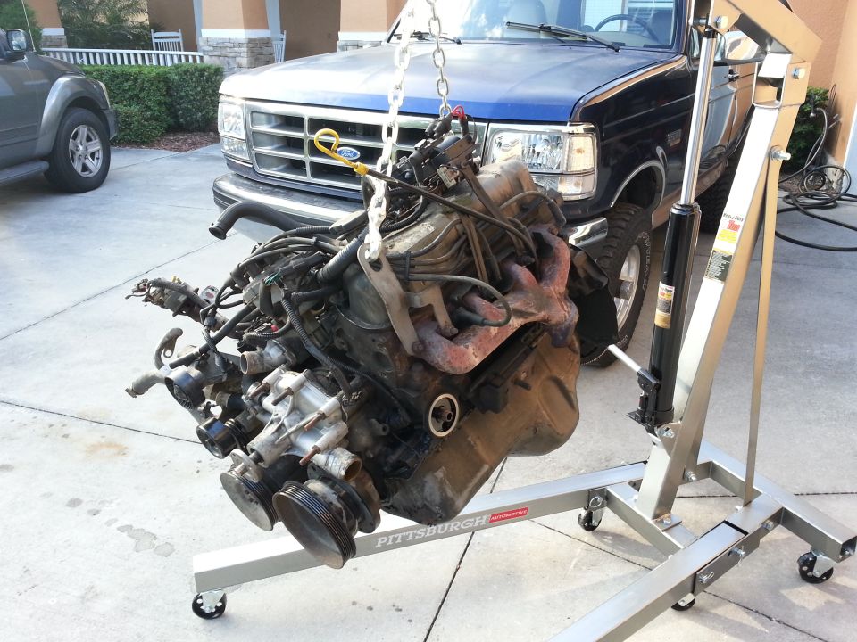 Blue Ford truck front with engine hoist lifting engine