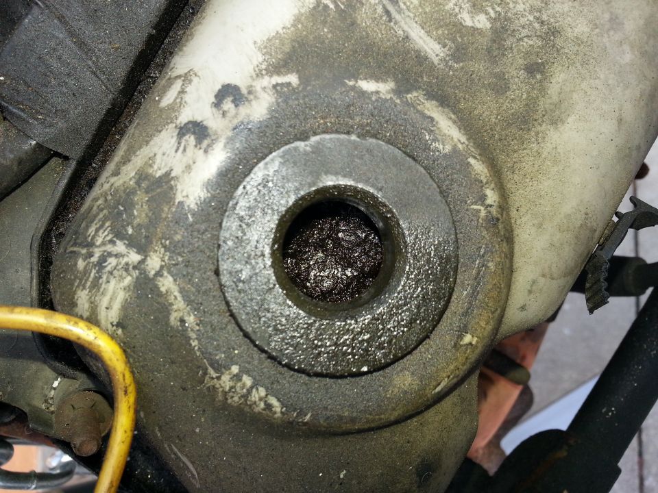 Close-up of a greasy metal component with a central hole filled with debris