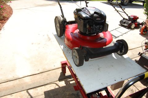 2006 Honda RANCHER - Two lawn mowers and a leaf blower are visible on a paved surface.