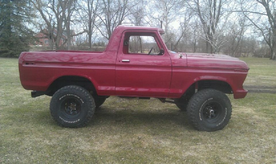 side view of red pickup truck with lifted suspension and off-road tires