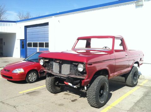 1978 Ford Bronco - Red 1977 Ford F-150 pickup truck and a red sedan parked outside a building.